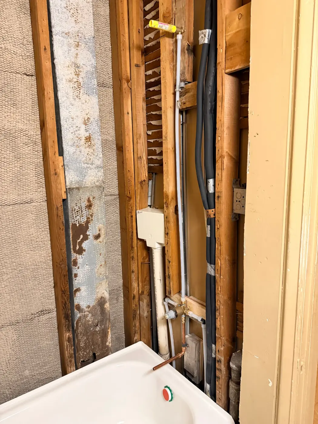 Open bathroom wall framing cleaned and treated during mold remediation with new plumbing rough-in visible