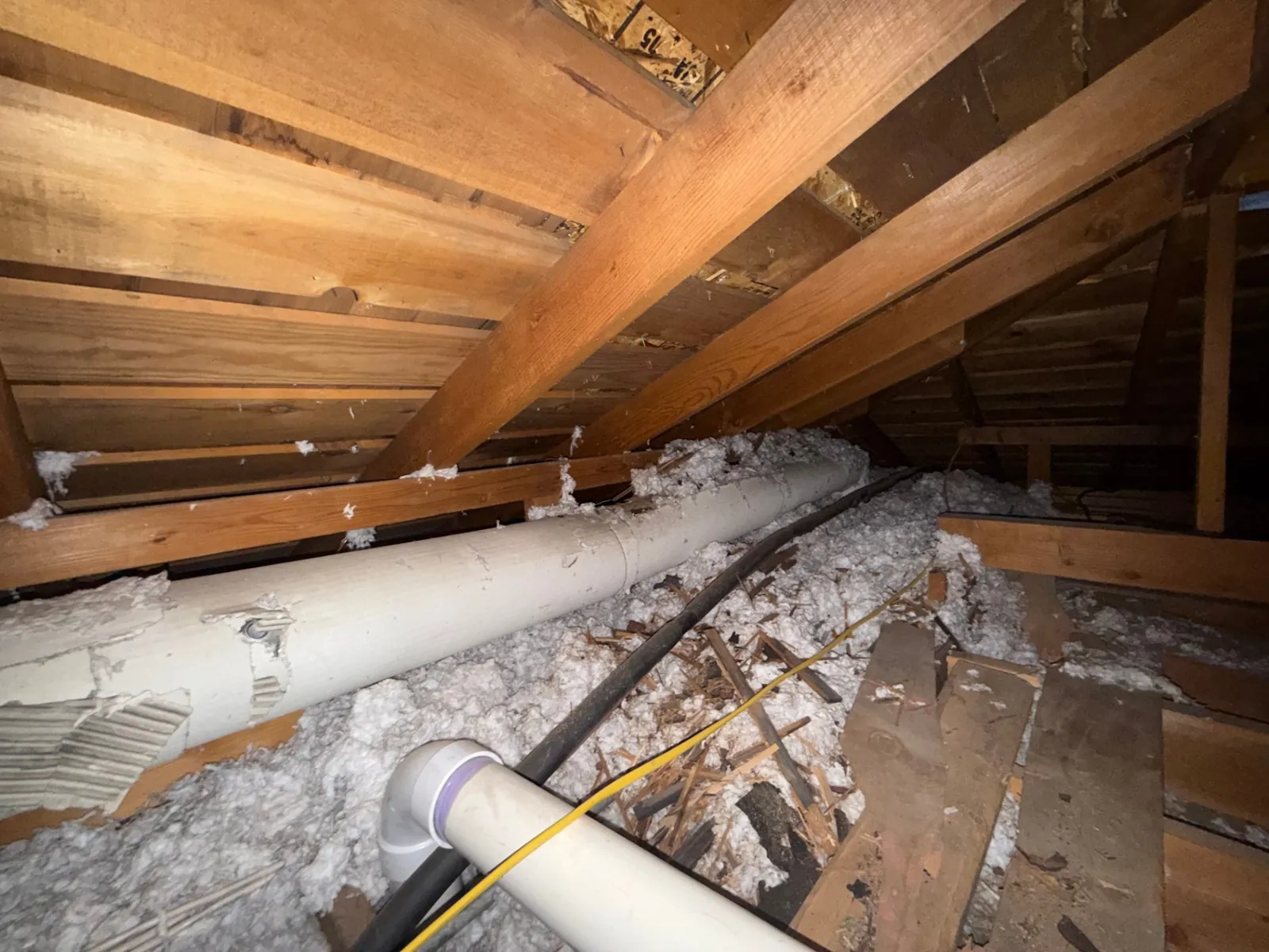 Deteriorated white asbestos pipe wrap on attic plumbing lines slated for safe removal by AHERA-certified Denver abatement crew